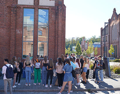 Erstsemester-Studierende beim Campusrundgang vor Halle 14 in einer Runde stehend