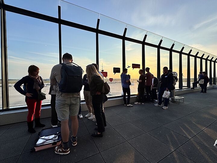 Besucher*innen auf der Besucherterrasse des BER bei Sonnenuntergang