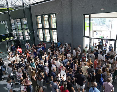 Alumni verlassen das Gebäude nach dem Gemsichaftsfoto und gehen zum Festgelände