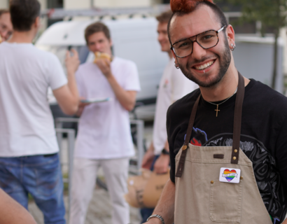 Junger Mann mit Grillzange lächelt in die Kamera