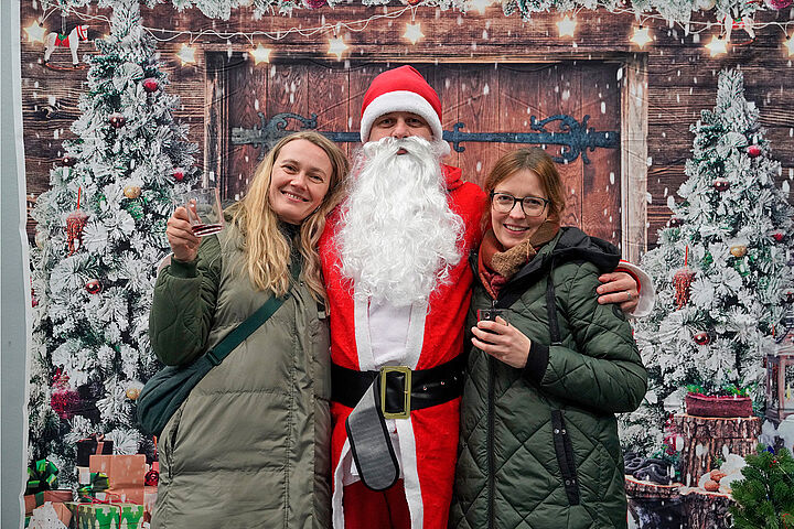 Haben sich ein Weihnachtsmannfoto „verdient“: Wie viele andere Kolleg*innen auch spendeten Susanne Dettmann und Desiree Grienitz (v.l.) auf unserem weihnachtlichen Get-together 2024 für das Hospiz und erhielten dafür ein Bild mit dem Weihnachtsmann