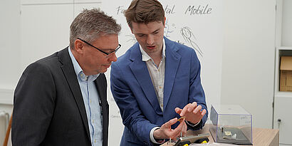 Zwei Teilnehmende der Eröffnung des Joint Technology Lab in Halle 21 schauen sich Mikrochips an