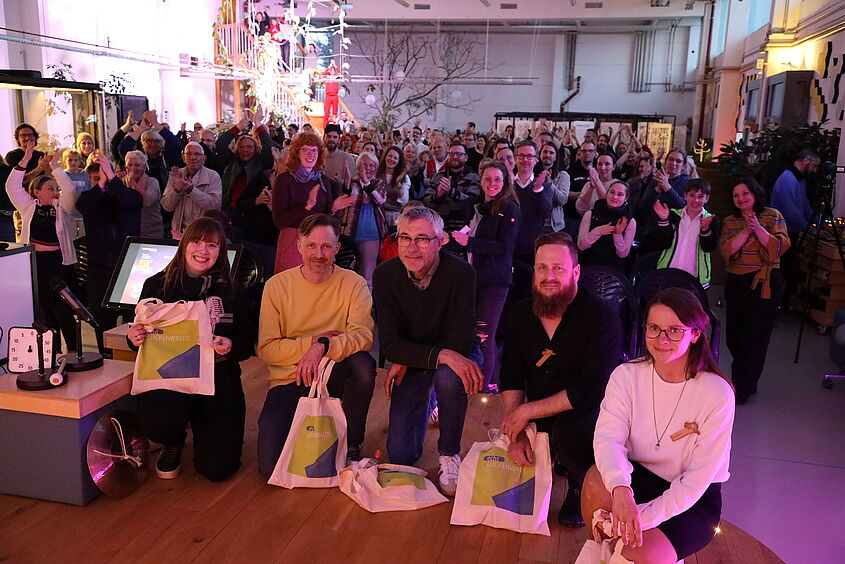 Die Gewinner des 4. Science Slam auf der Bühne und das Publikum im Hintergrund