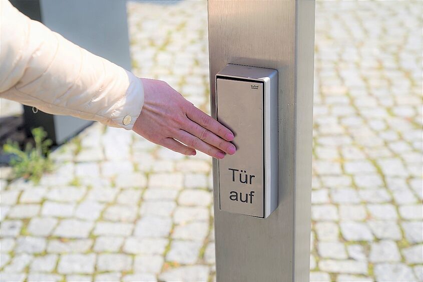 Barrierencheck, Hand drückt Türöffner für Automatiktür
