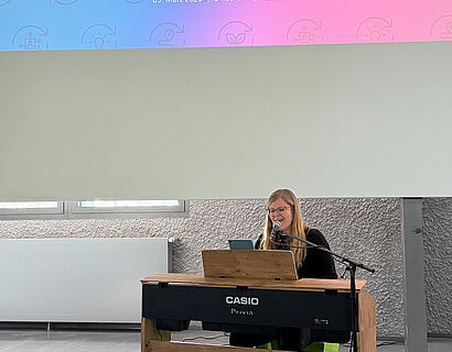 In diesem Bild ist eine Person zu sehen, die etwas singt und an einem Klavier spielt.