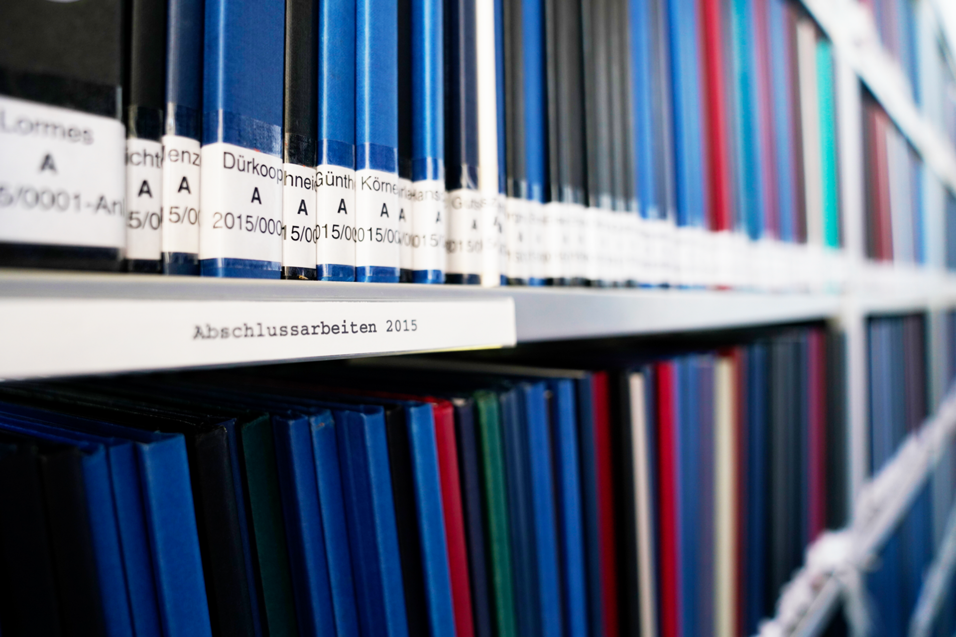 Abschlussarbeiten Regal Hochschulbib Bücher in einem Bibliotheksregal mit Beschriftung "Abschlussarbeiten"