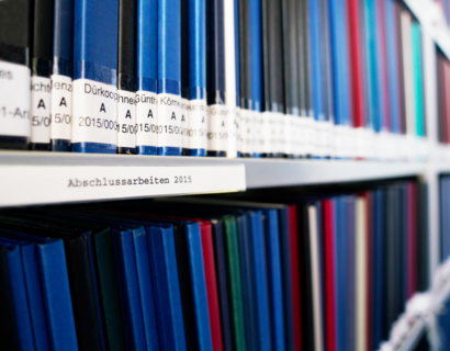 Bücher in einem Bibliotheksregal mit Beschriftung "Abschlussarbeiten"