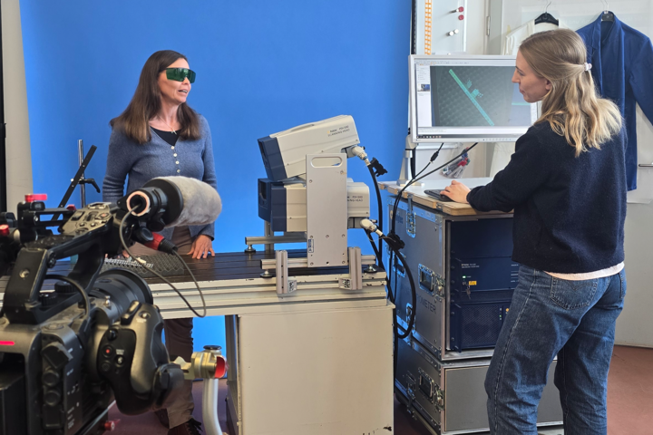 Imagevideo labor Eine Kamera im Vordergrund filmt eine Person an einem Pult