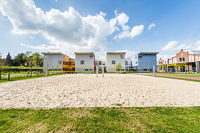 Blick auf das Beachvolleyballfeld und Haus 15