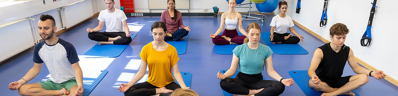 Studierende beim Meditieren bei einem Yoga-Kurs der Hochschule