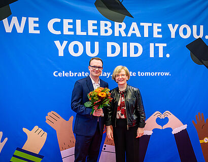 Prof. Ulrike Tippe und ein Absolvent posieren bei der Verabschiedung 2025 für ein Foto