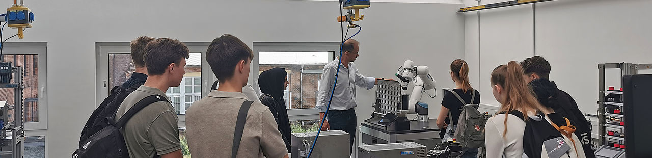 Schülerinnen und Schüler im Automatisierungstechnik-Labor beim Betrachten der Technik