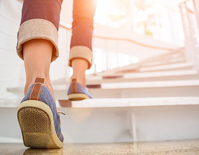 Nahaufnahme von Füßen in Froschperspektive, die eine Treppe hinaufgehen
