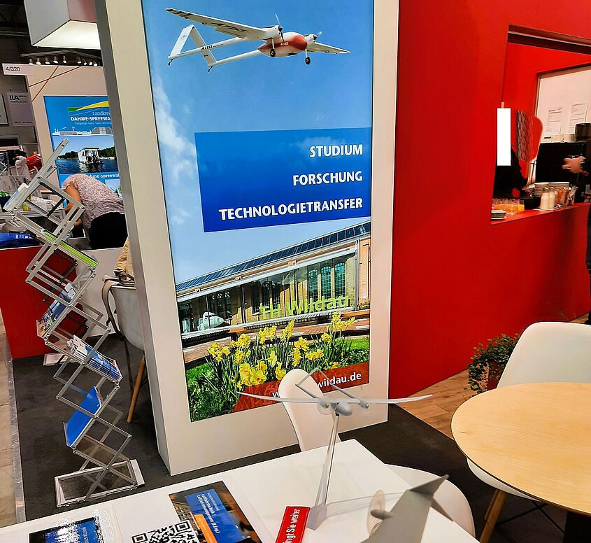 Vom 5. bis 9. Juni 2024 präsentiert sich auch die TH Wildau mit einem Stand auf der Internationalen Messe für Luft- und Raumfahrt (ILA) Bild: Christine Richert / TH Wildau Messestand der TH Wildau auf der ILA mit Ausstellunsstücken und Informationsmaterial