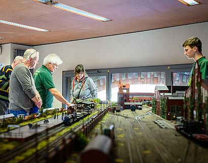Personen stehen um eine Miniatur-Modellbau-Anlage des Wildauer Bahnhofs