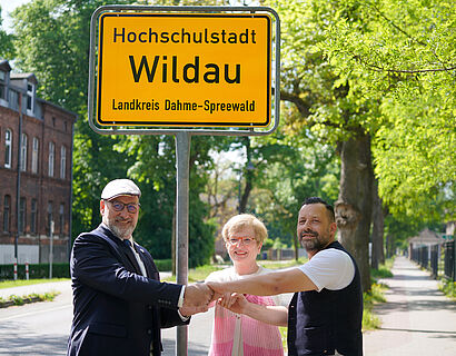 Wildaus Bürgermeister Frank Nerlich, TH-Wildau-Präsidentin Prof. Ulrike Tippe und Ronny Richter, Vorsitzender der Stadtverordnetenversammlung bei einer symbolischen Geste des Zusammenhalts vor dem neuen Orteingangsschild mit der Aufschrift "Hochschulstadt Wildau"