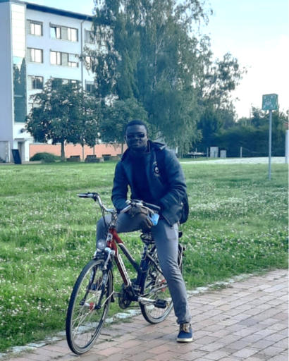 Ein Student auf einem Fahrrad vor einem Universitätsgebäude auf dem Campusgelände.