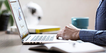 Laptop auf Schreibtisch mit Hand von Person