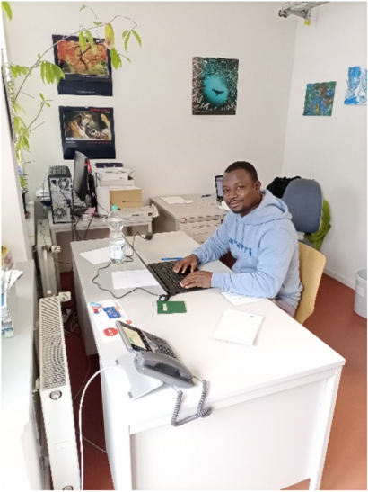 Ein Mann sitzt an einem Schreibtisch in einem Büro und arbeitet an einem Laptop.
