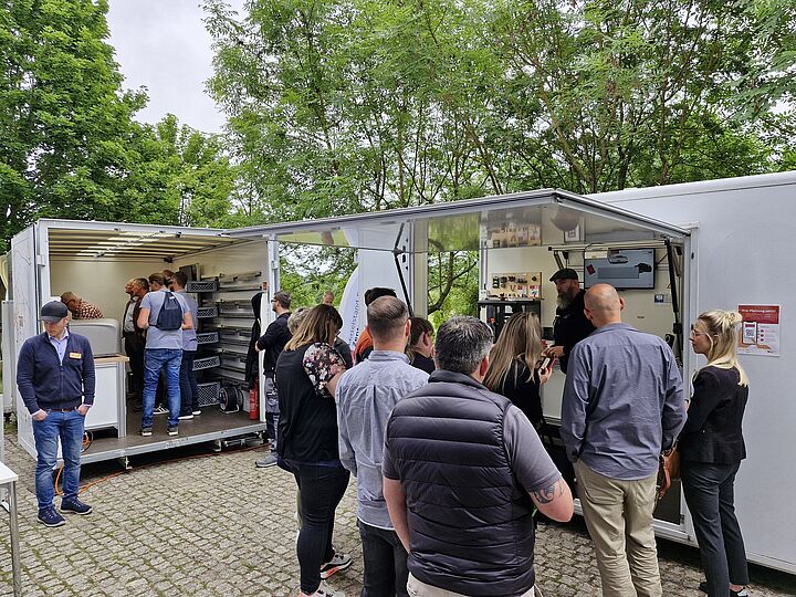 Besucher in der mobilen digitalen Fabrik, die Anwendungsbeispiele rund um Digitalisierung und Künstliche Intelligenz im produzierenden Gewerbe bietet.