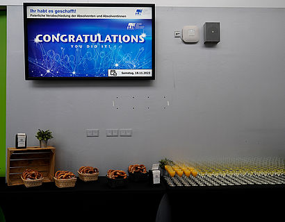 Blick auf das Buffet und den Screen mit der Folie "Congratulations" bei der feierlichen Verabschiedung der Absolventinnen und Absolventen 2023 des Fachbereichs WIR