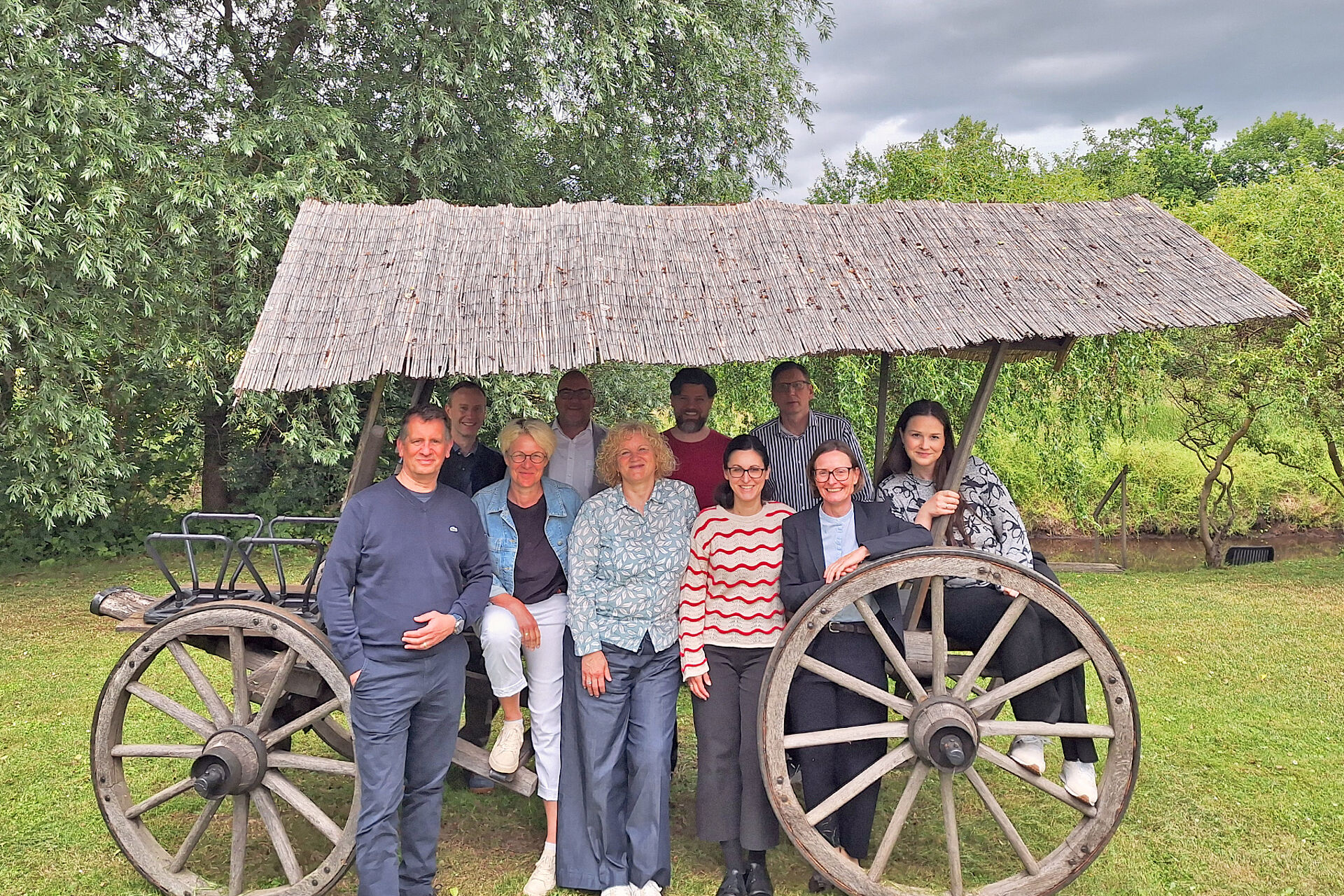 Gruppenfoto im Grünen rund um einen traditionellen hölzernen Spreewald-Wagen 