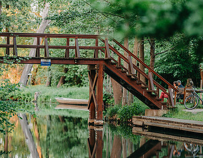 Braune Holzbrücke über einem schmalen Flusslauf