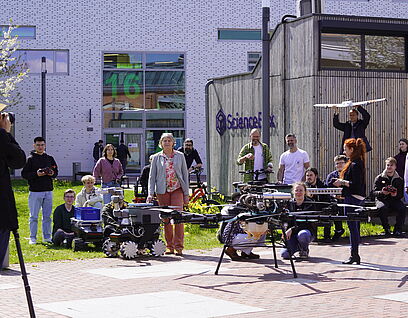 Personen stehen mit Flugobjekten, darunter Drohnen, auf dem Campus der TH Wildau und werden fotografiert