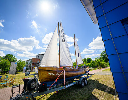 Segelboot steht auf dem Campus der TH Wildau im Hintergrund blauer Himmel und Sonnenschein