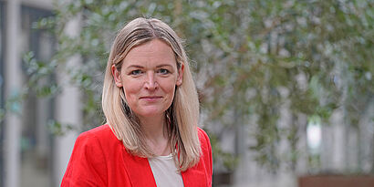 Bild einer Frau mit blonden Haaren und rotem Blazer