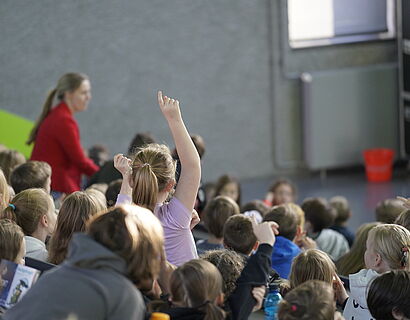 Kinderuni Winter Edition 2024 - EIn Kind meldet sich aus der Menge im Audimax und stellt eine Frage