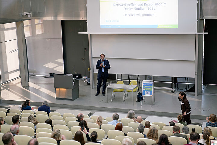 Mann steht in einem Hörsaal vorn und hält einen Vortrag