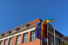 Europäische, deutsche und ukrainische Flagge vor Haus 13