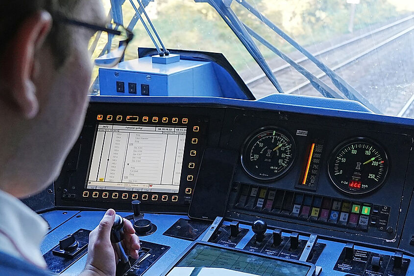 Ein Zugführer von hinten fotografiert bei der Arbeit im Zug mit der Hand am Steuerhebel