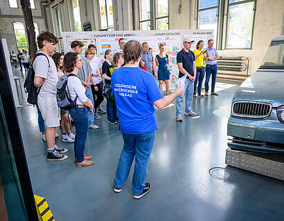 Student der TH Wildau bei einer Campusführung in Halle 14 an einem Automodell.