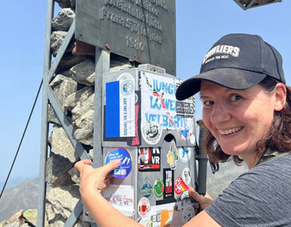Person bringt Sticker an Gipfelkreuz an
