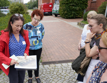 Eine Frau zeigt einer Gruppe ein Bild mit einer alten Zeichnung