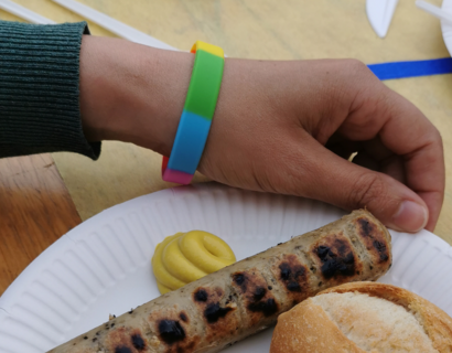 Ein gegrilltes Würstchen und ein Brötchen auf einem Pappteller