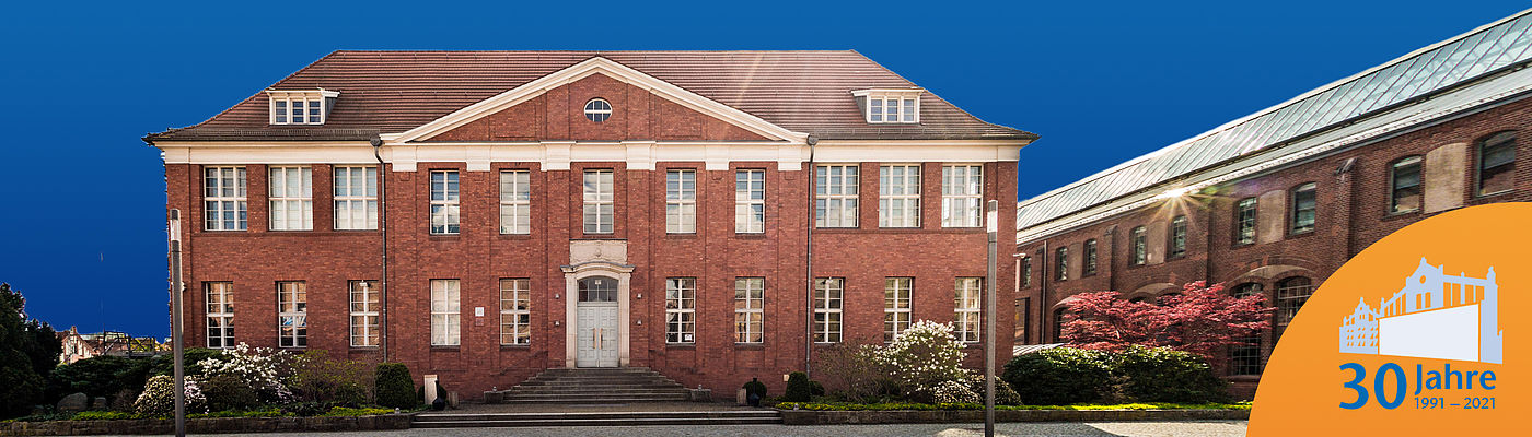 Haus 13 vor blauem Hintergrund mit 30-Jahre-Logo auf orangenem Icon