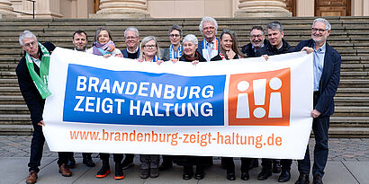 Teilnehmende der Initiative "Brandenburg zeigt Haltung" halten großes Banner mit Schriftzug 