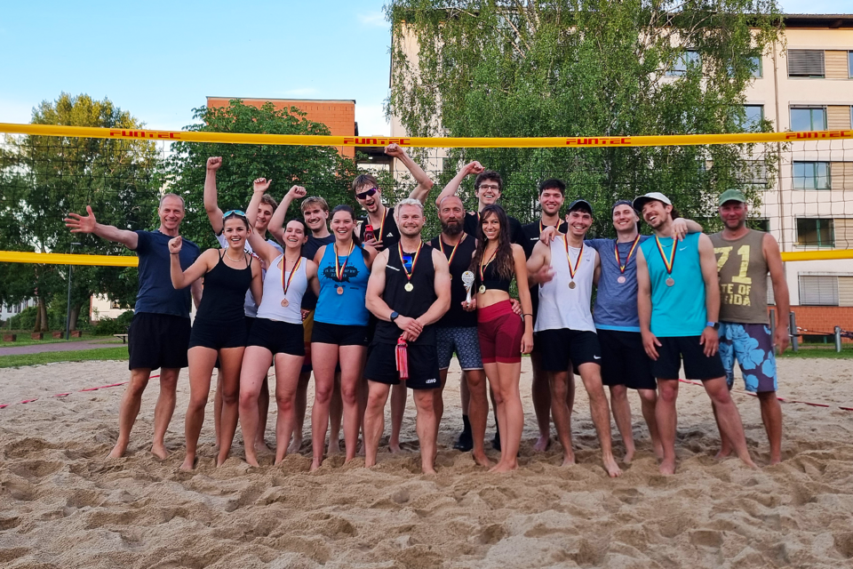 Beachturnier 2026 Gruppe Titelbild Gruppe von Menschen auf einem Beachvolleyballfeld