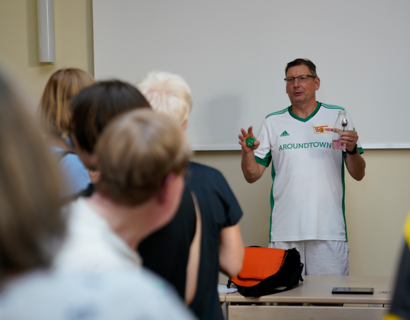 Mann steht vor weißer Tafel und redet vor Zuhörenden