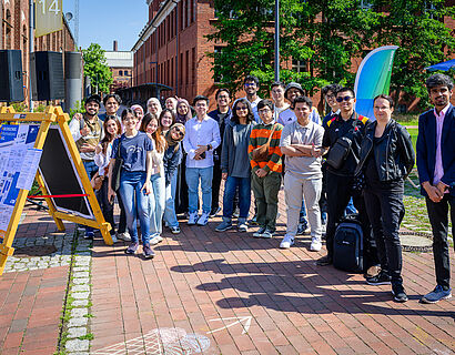 Besucherinnen und Besucher des HIT 2024 der TH Wildau bei einem Gruppenfoto an einem großen Plakataufsteller. 