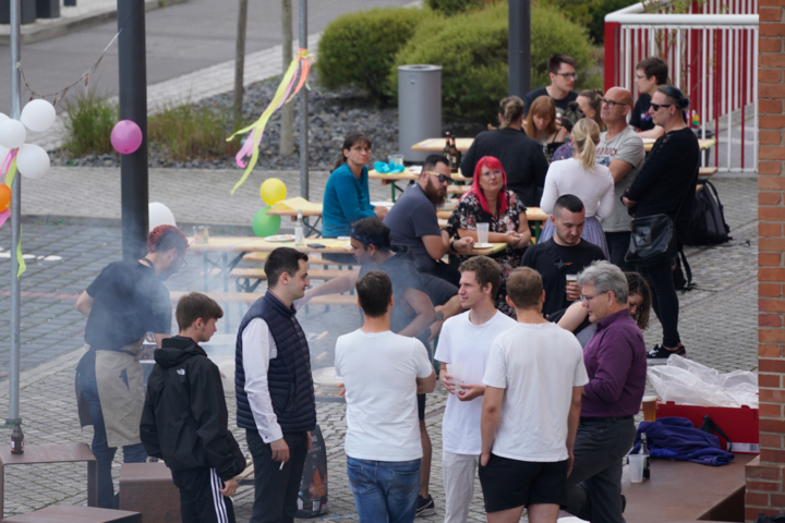 Menschen sitzen und stehen an Bierbänken und unterhalten sich