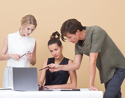 Two woman and one man looking at the laptop 