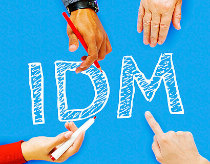 Buchstaben I, D und M auf blauem Hintergrund mit Händen, die darauf zeigen