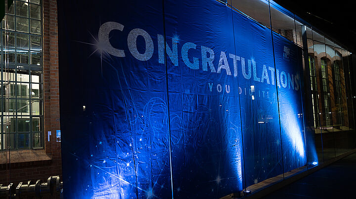Scheinwerfer, die auf das "Congratulations" Banner in Halle 17 leuchten