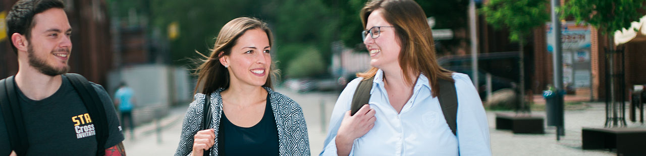 Drei Studierende laufen über den Campus